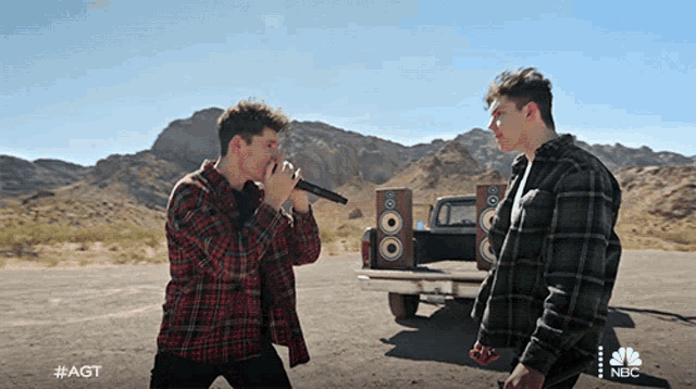 two men singing in front of a truck with nbc written on the bottom