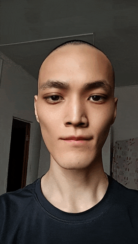 a young man with a shaved head looks at the camera