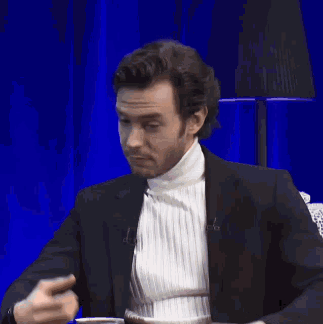 a man wearing a white turtleneck and a black jacket talking