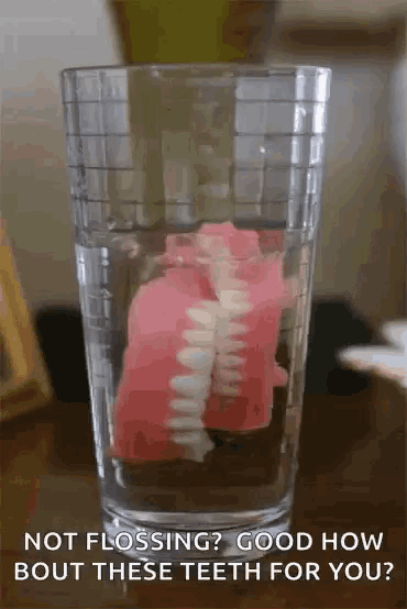 a glass of water with a fake teeth in it