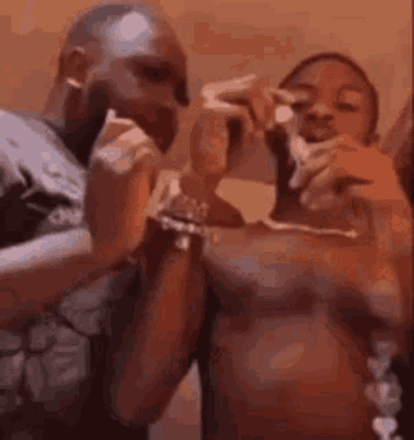 a couple of men are standing next to each other and eating a piece of pizza .