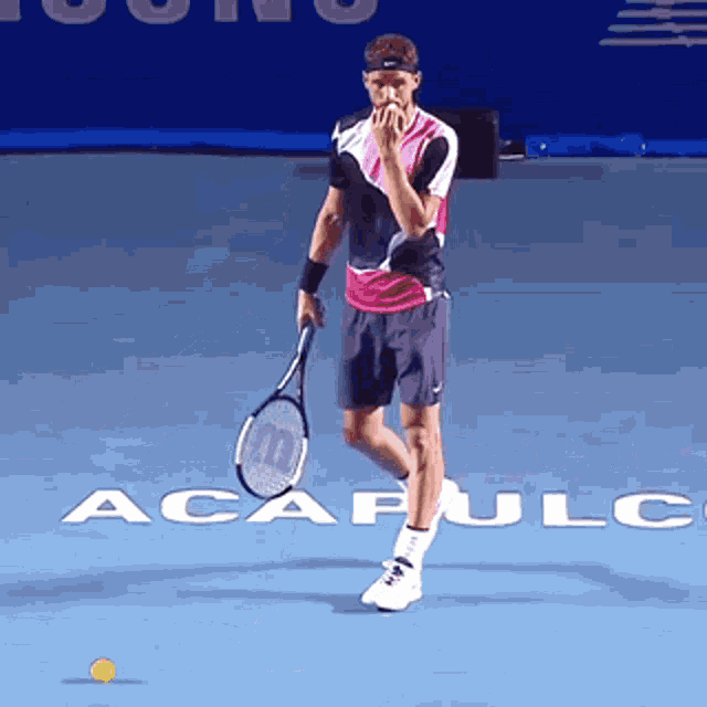 a man holding a tennis racquet in front of a sign that says acapulc