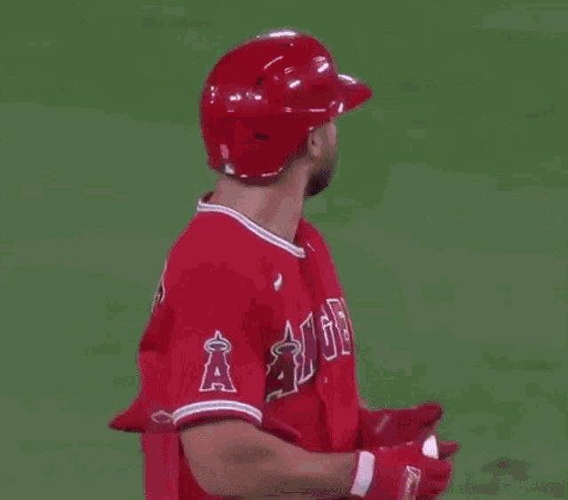 a baseball player wearing a helmet and a red jersey with the word angels on it is standing on a field .