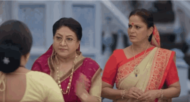 three women are standing next to each other and one has a red bindi on her forehead