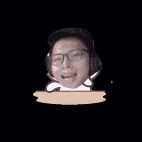 a man wearing glasses and headphones is sitting at a table with his mouth open .