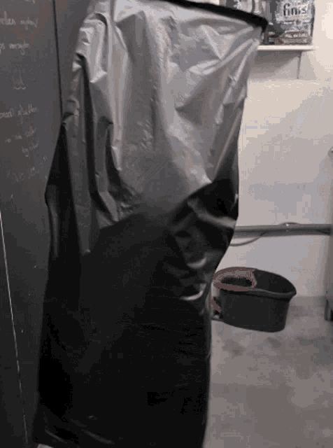 a black bag is hanging on a wall next to a shelf with a can of finish on it