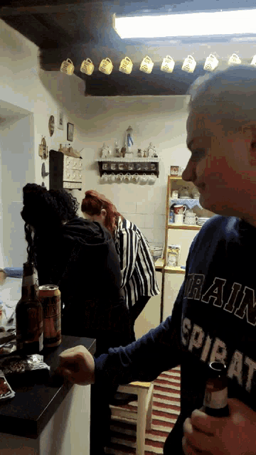 a man wearing a rain sweatshirt holds a beer bottle