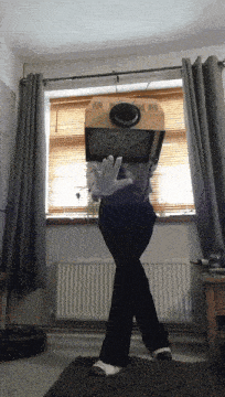 a person standing in front of a window with a box on their head that says ' o ' on it