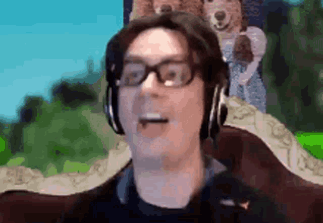 a man wearing glasses and headphones is sitting in front of a screen .
