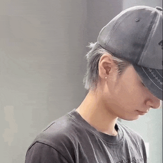 a man wearing a baseball cap and a black shirt is looking down .