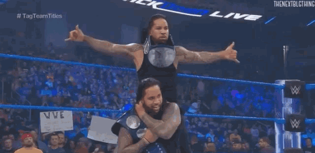 a wrestler is carrying another wrestler on his shoulders in a wrestling ring