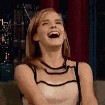 a woman is laughing while sitting on a couch with her mouth open .