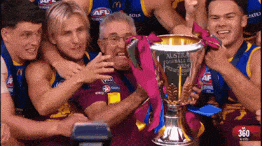 a group of soccer players are holding up a trophy that says australia football league