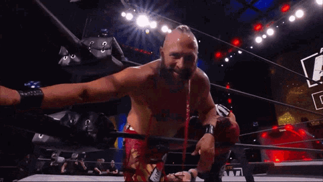 a man in a wrestling ring with the letter a on the screen behind him