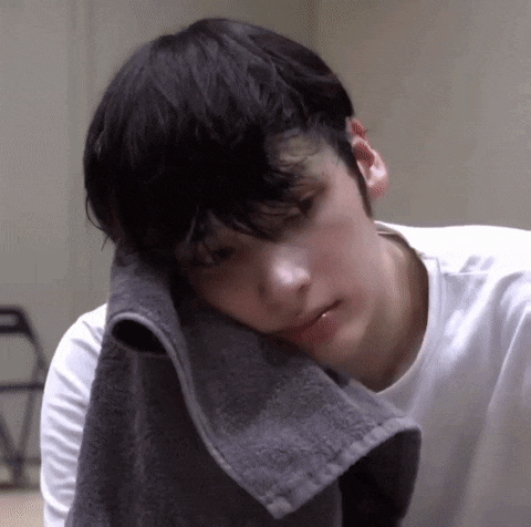 a young man is laying down with a towel on his head .