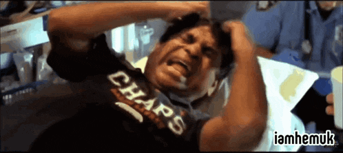a man in a chaps shirt is laying in a hospital bed with his hands on his head