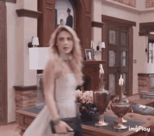 a woman in a white dress is walking through a living room .