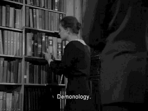 a woman is taking a book from a bookshelf in a library and talking about satanism .