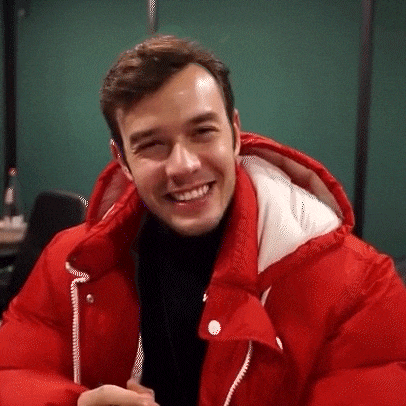 a man wearing a red jacket with a hood is smiling for the camera .