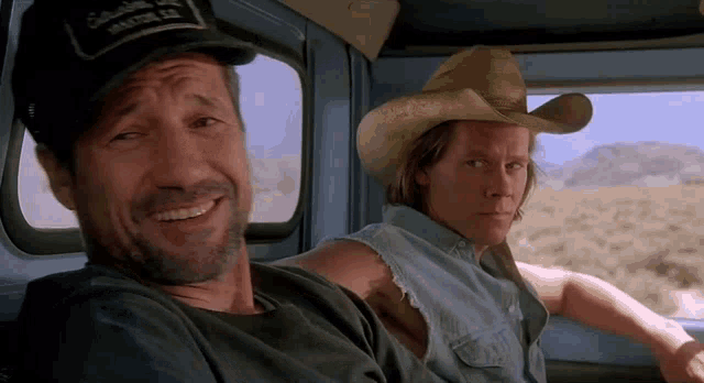 two men wearing cowboy hats are sitting in a truck