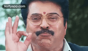 a man with glasses and a mustache is giving a thumbs up sign .