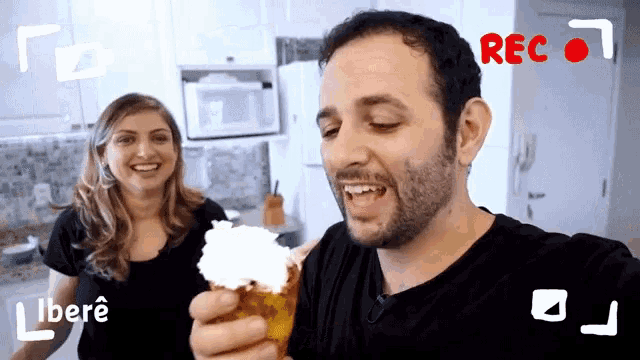 a man is holding a cone with whipped cream while a woman looks on and the word rec is visible