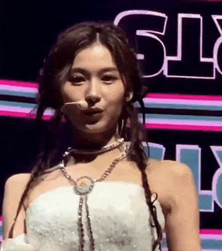 a woman in a white dress is standing on a stage with a microphone in her mouth .