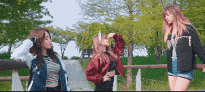 three girls are standing next to each other with one wearing a jacket with the letter t on it