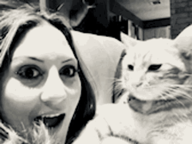a woman is sitting on a couch holding a cat in her arms .