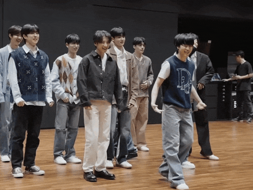 a group of young men are standing on a wooden floor and one of them is wearing a blue vest with the letter p on it