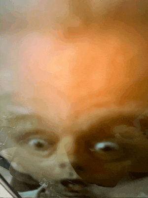 a close up of a person 's face behind a glass container
