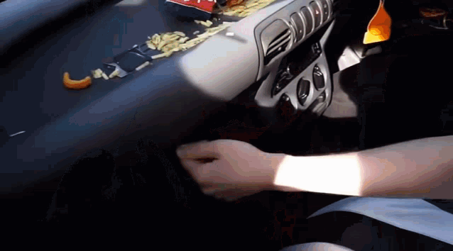 a person is sitting in a car with chips on the dashboard