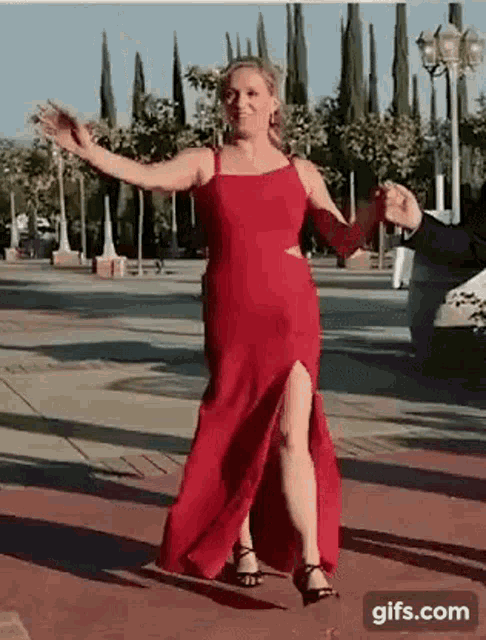 a woman in a long red dress is dancing with a man in a suit .