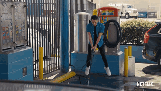 a man is using a high pressure hose at a car wash with a netflix logo in the background