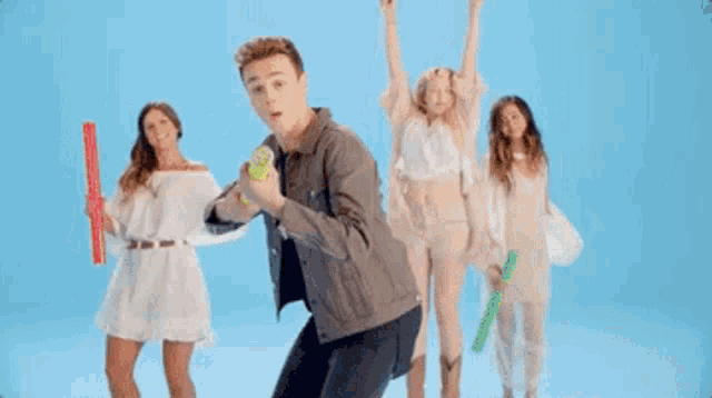 a man in a denim jacket is holding a green water gun in front of three women