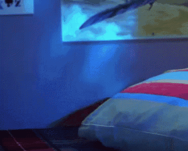 a cartoon character is laying on a bed with a blue light behind him