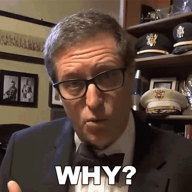 a man wearing glasses and a bow tie says " why "