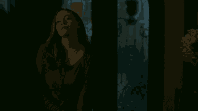 a woman is standing in a dark room looking at the camera