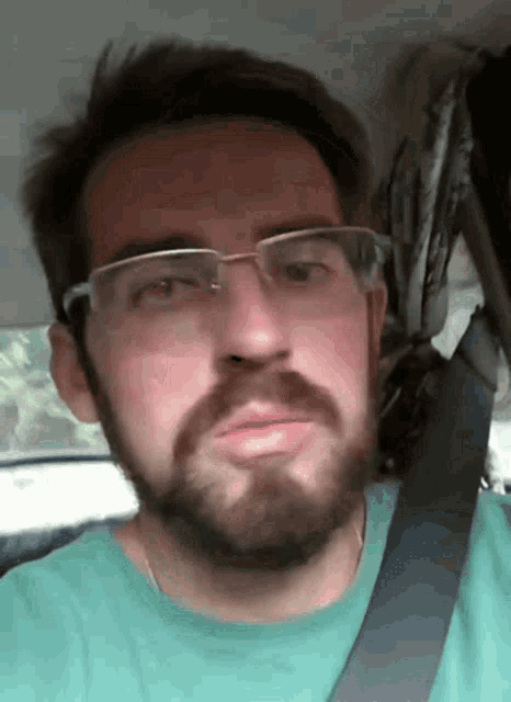a man with a beard wearing glasses and a green shirt