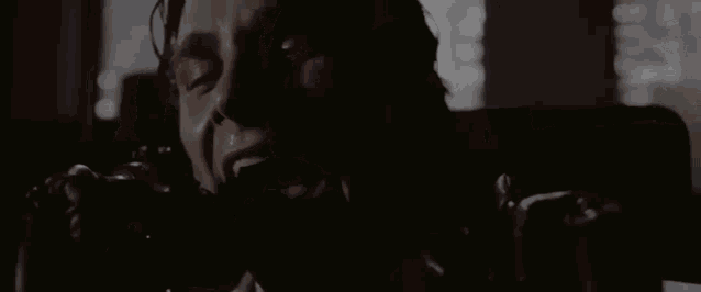 a close up of a man talking on a telephone with his eyes closed .