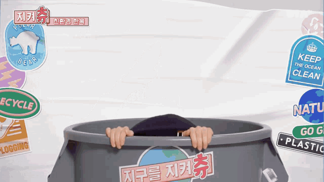 a person is sticking their head out of a trash can surrounded by stickers including one that says " keep the ocean clean "
