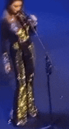 a woman is singing into a microphone in a blue room