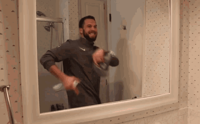 a man in a nike shirt is brushing his teeth in a bathroom mirror