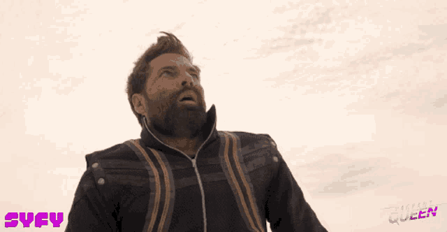 a man with a beard is screaming in front of a sky with a syfy logo in the corner