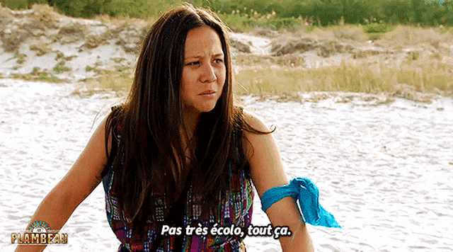 a woman is standing on a beach and says pas tres ecolo tout ca.