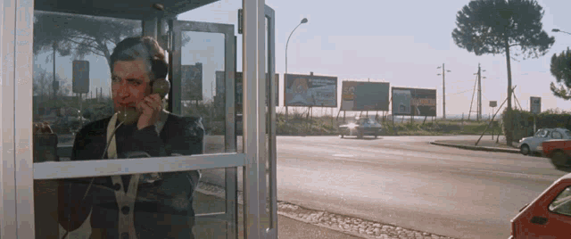 a man is talking on a phone while standing in a booth