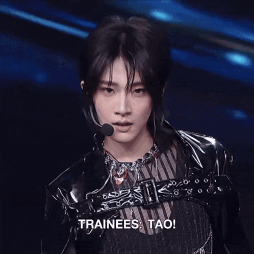 a young man wearing a black leather jacket and a necklace says trainees tao