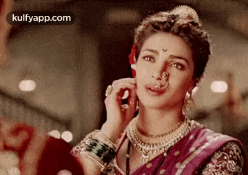 a woman wearing a nose ring and a necklace is looking at a man .