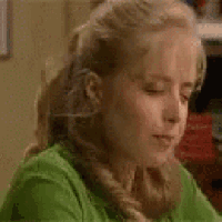 a close up of a woman in a green shirt holding her hair .