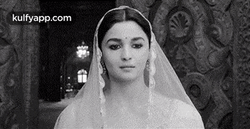 a black and white photo of a woman wearing a white veil .